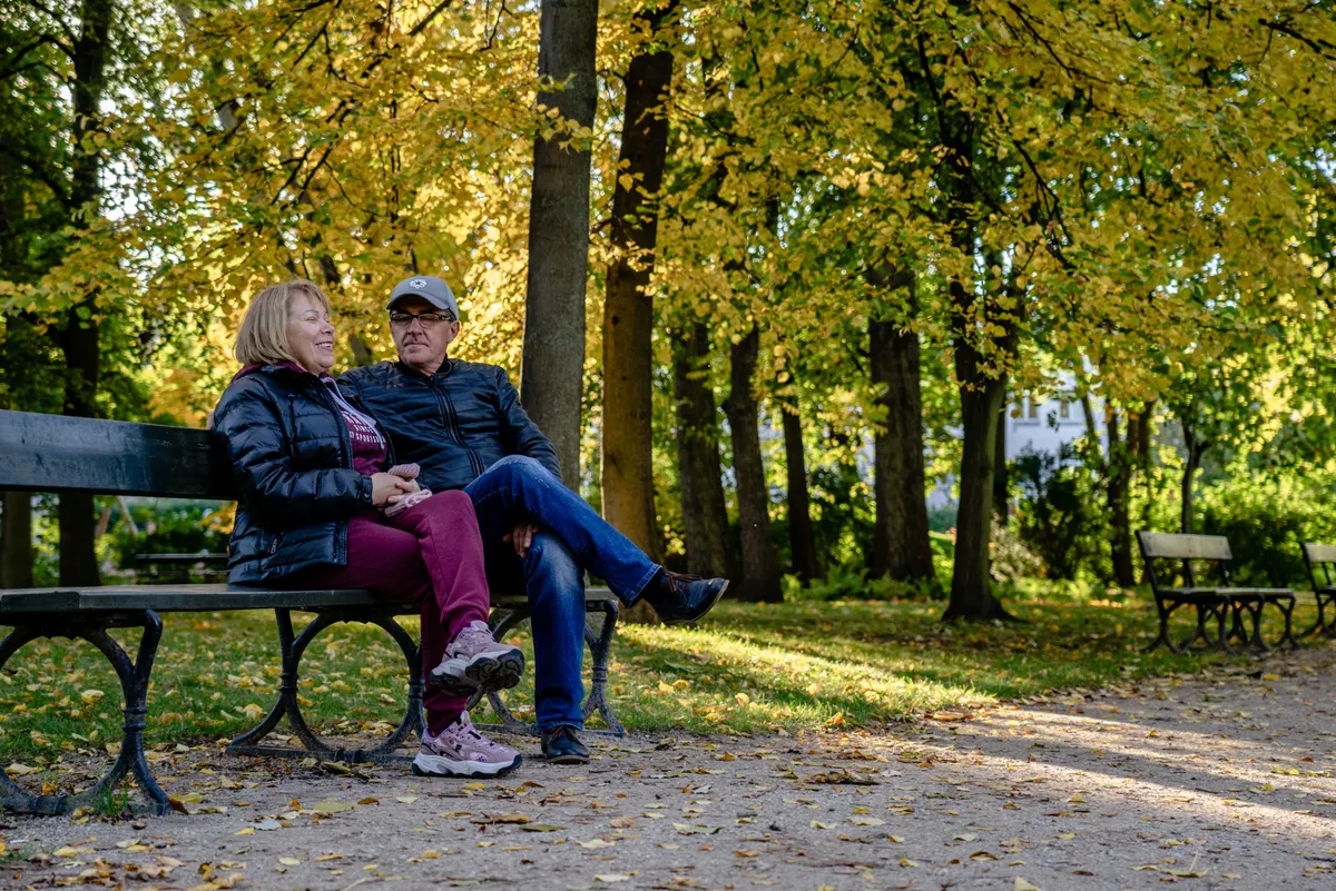 Older couple sitting on a park bench in autumn