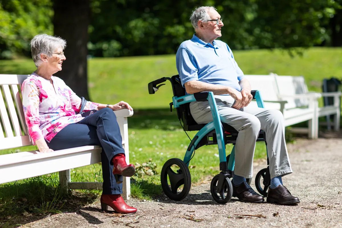 Older adults relaxing in a park with a mobility aid