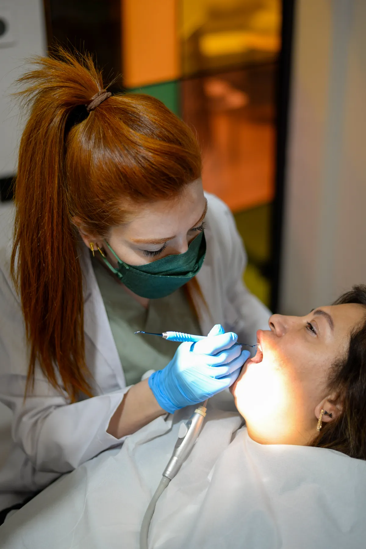 Dentist examining a patient under a dental light