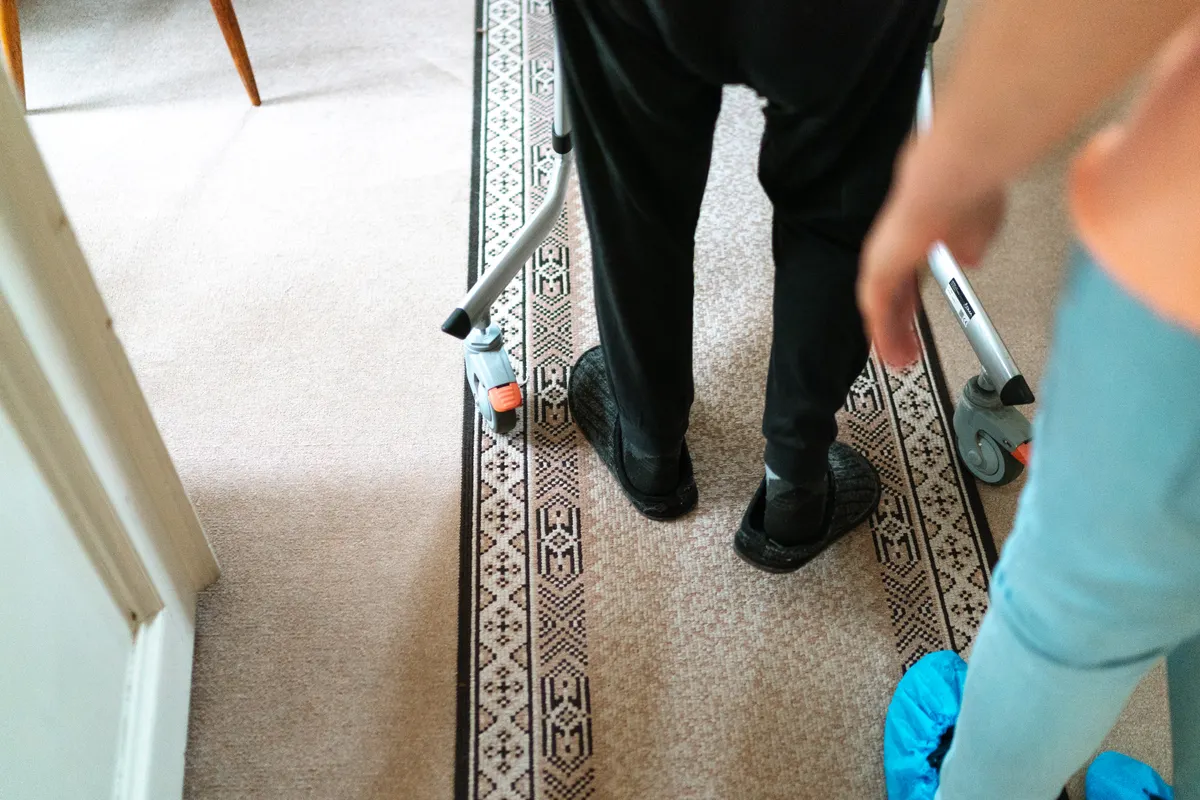 Person using a walker with assistance indoors