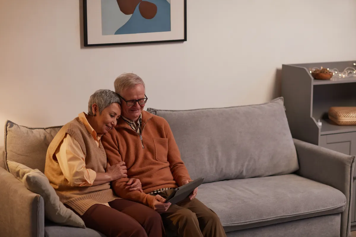 Older couple using a tablet together on a sofa