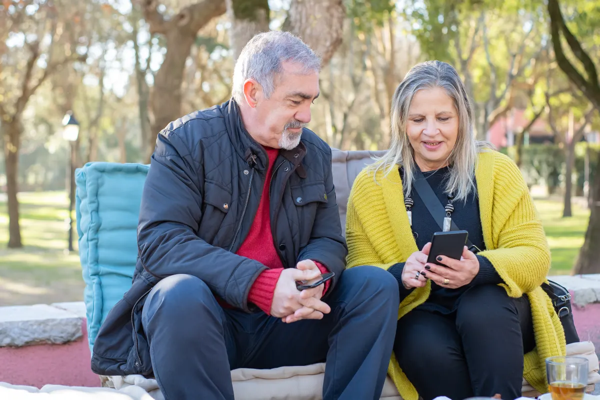 Older couple using smartphones together in a park
