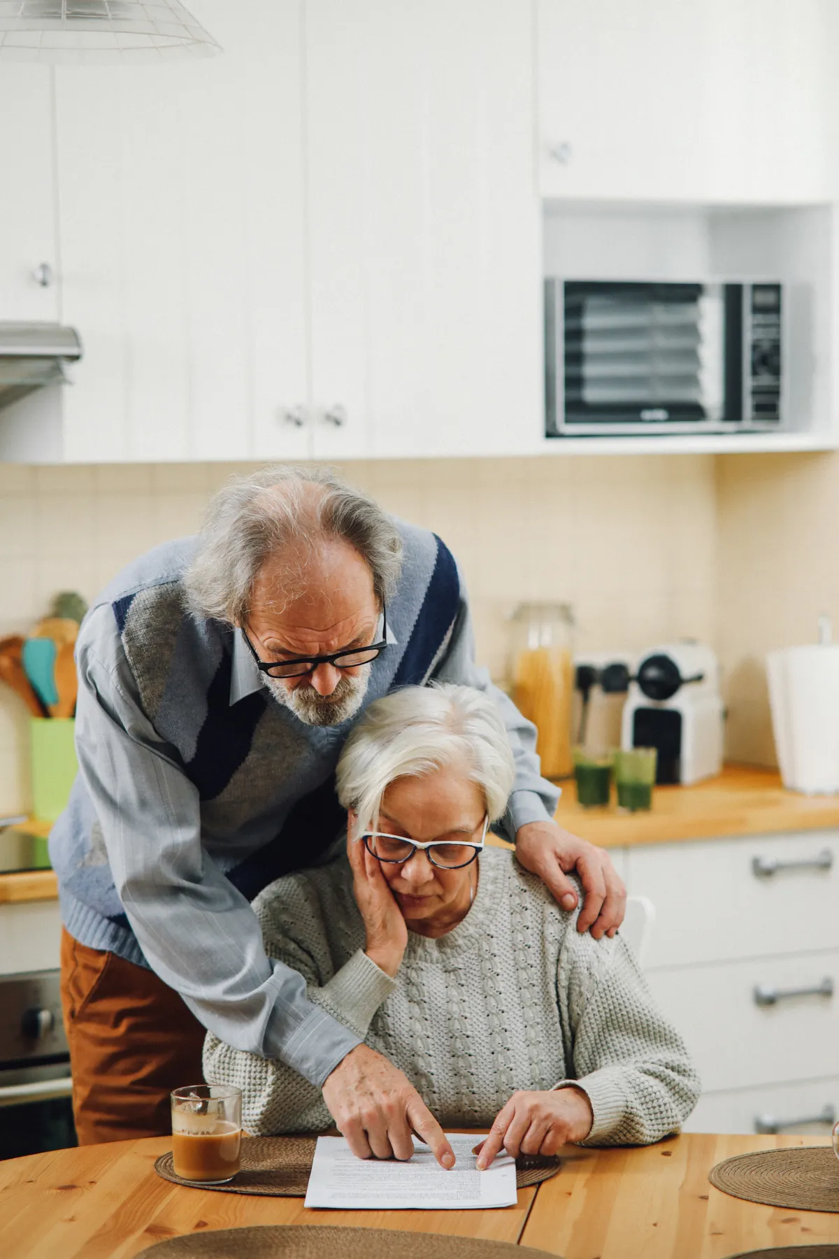 Older couple reading paperwork in their kitchen