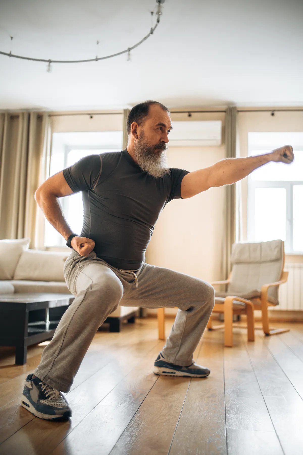 Man stretching at home beside a chair