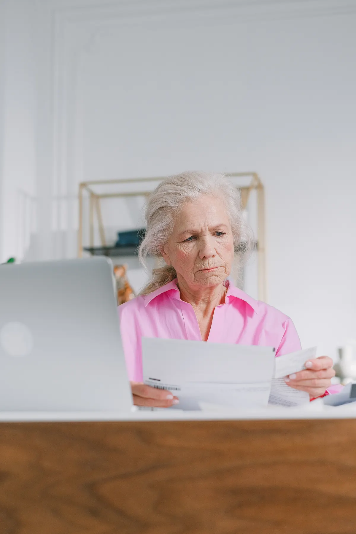 Older woman reading paperwork at her desk