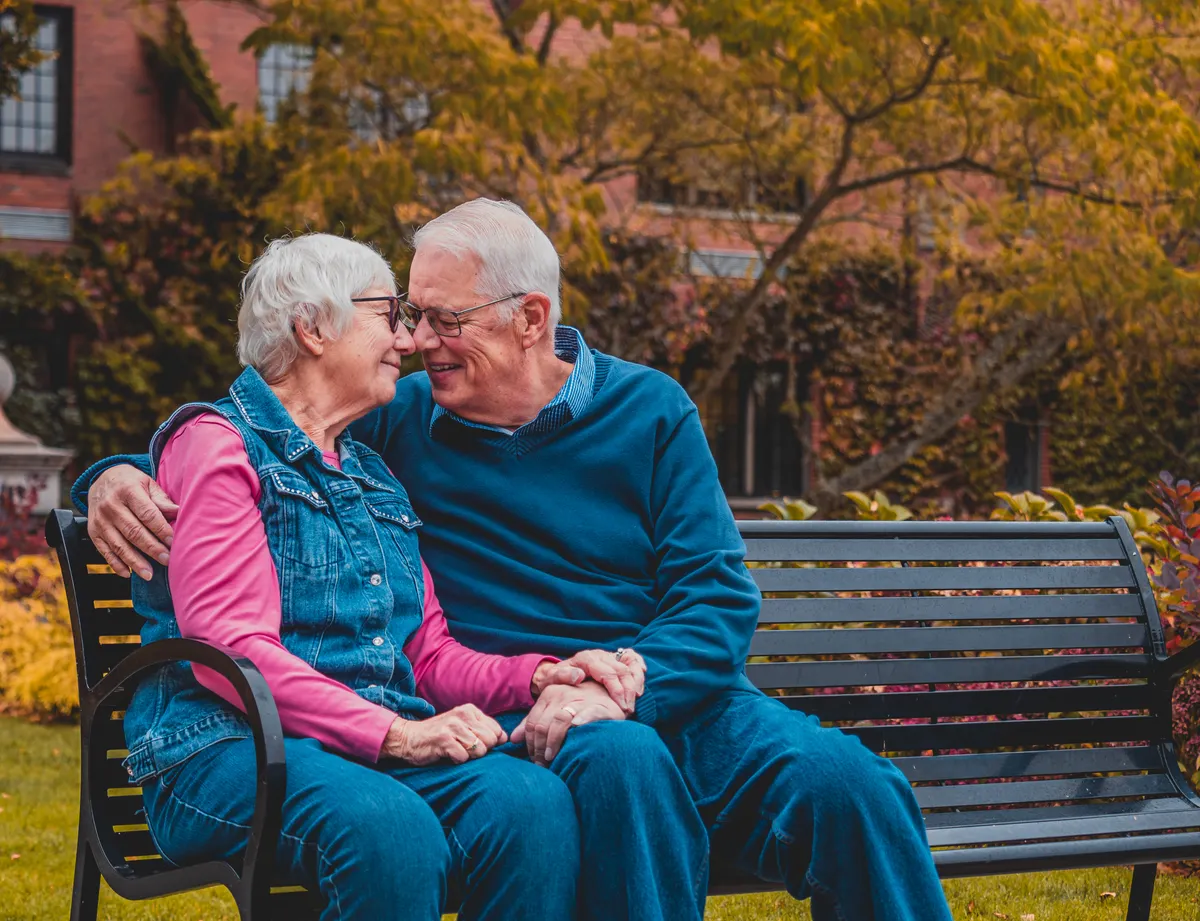 Older couple holding hands on a park bench