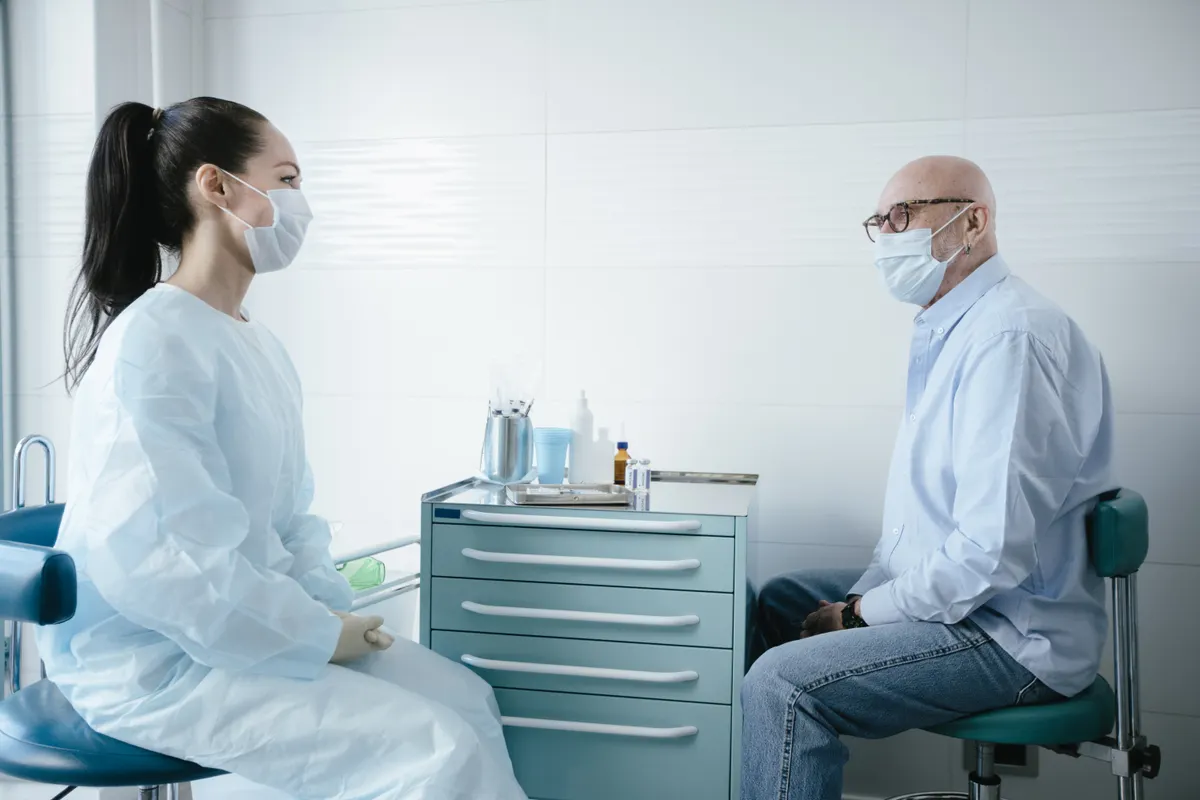Older man speaking with a healthcare professional in an examination room