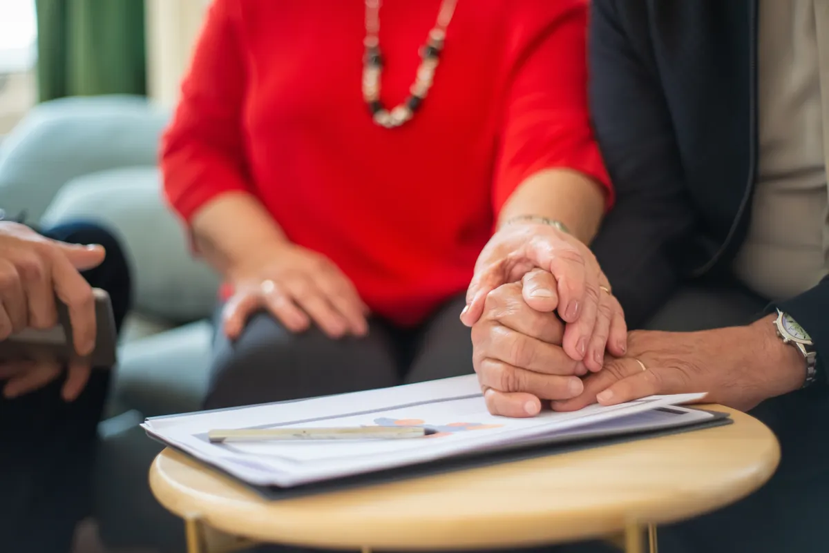 Couple holding hands over documents at a meeting