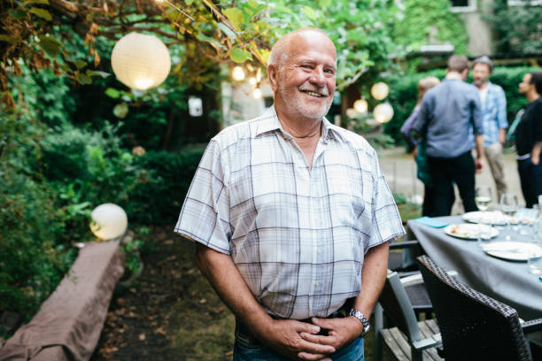 A smiling elderly man enjoying an outdoor gathering with friends, symbolizing improved health and well-being.