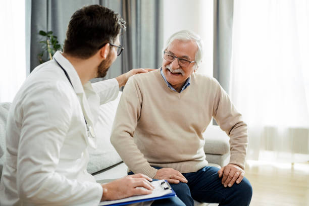 Senior man with glasses smiling while consulting a doctor in a modern medical office, discussing health and comfort solutions.

