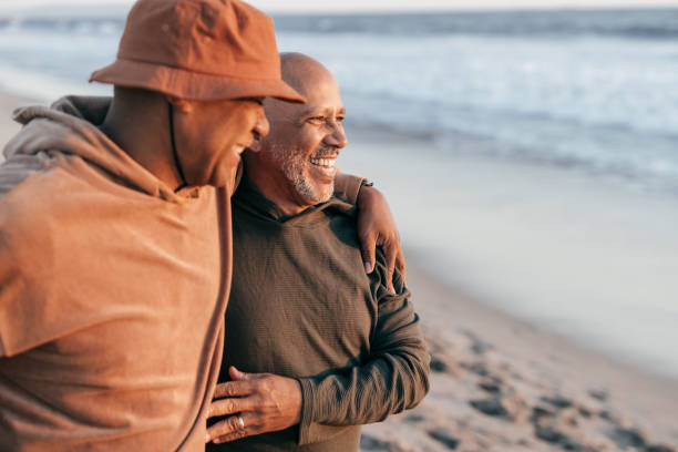 Two smiling senior men embracing on a beach, representing the comfort and care provided in long-term care settings with professional nursing support.