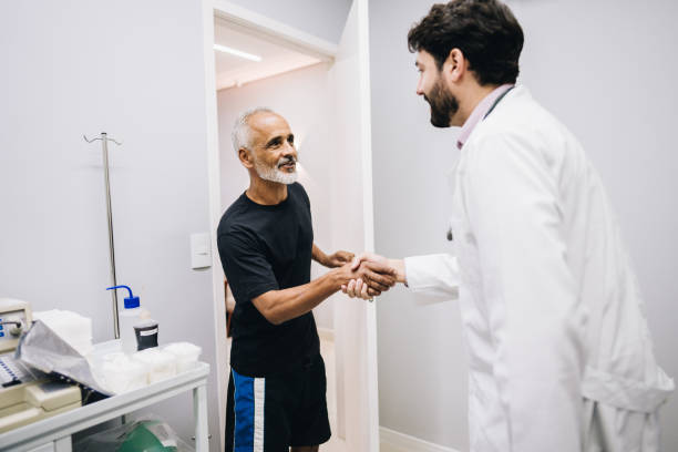 Senior patient shaking hands with a doctor in a medical office while discussing testosterone replacement therapy (TRT) and insurance coverage.