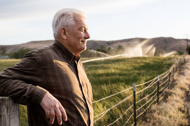 "Senior man standing by a wooden fence in a rural setting, representing Medicare beneficiaries considering financial options for coverage."

