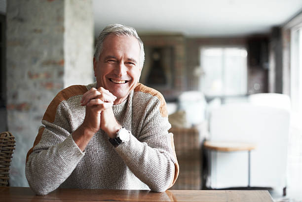 A happy elderly man sitting indoors, symbolizing confidence in understanding Medicare coverage for bathroom safety equipment and additional coverage options.