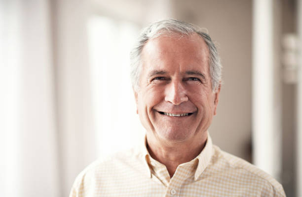 A smiling elderly man indoors, representing confidence in choosing a Medicare-approved supplier for bathroom safety equipment.