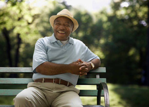 "Smiling senior man wearing a hat sitting on a park bench, representing Medicare Part B beneficiaries who may benefit from coverage for medications and treatments."

