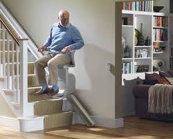 An elderly man sitting on a staircase in a well-lit home, assessing the suitability of his stairs for a stair lift installation.