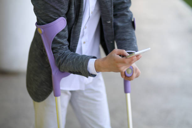 A person using purple crutches while holding a smartphone, representing the use of durable medical equipment (DME) covered by Medicaid for individuals with mobility needs.

