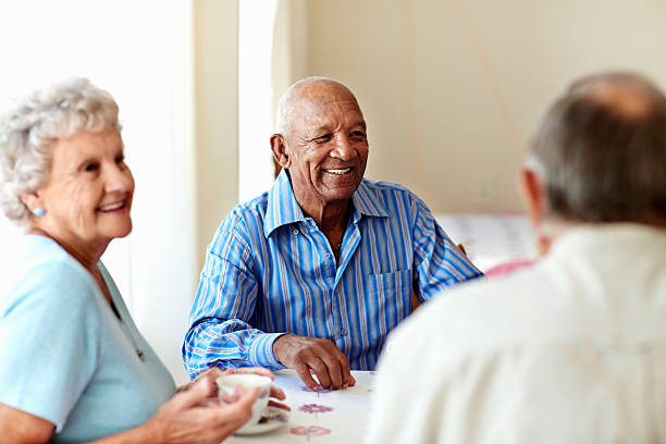 "Group of smiling seniors sitting at a table, enjoying coffee and conversation in a bright, indoor setting." 